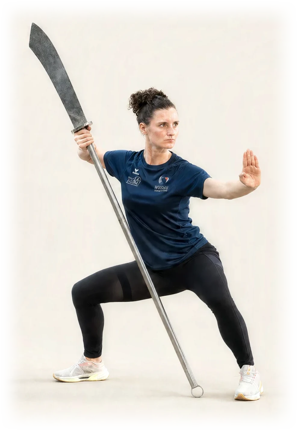 Pratiquante du Kung Fu Club Nantais en posture basse, une arme longue traditionnelle à la main